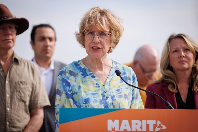 A woman speaks at a press conference behind a podium.