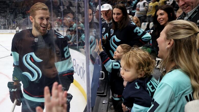 SEATTLE, WASHINGTON - APRIL 13: Alex Wennberg #21 of the Seattle Kraken greets his family Felicia and Rio through the glass during warmups before the game against the Vegas Golden Knights at Climate Pledge Arena on April 13, 2023 in Seattle, Washington. (Photo by Steph Chambers/Getty Images)