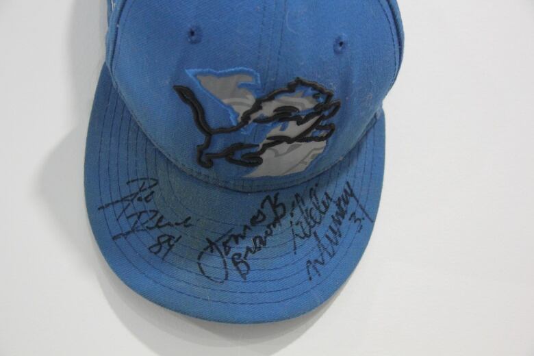 A cap with a lion logo and three autographs.