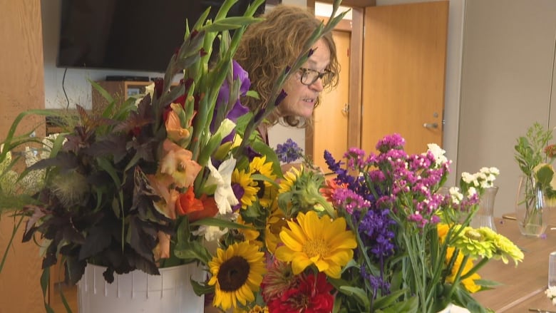 A woman arranging a bouquet of flowers.