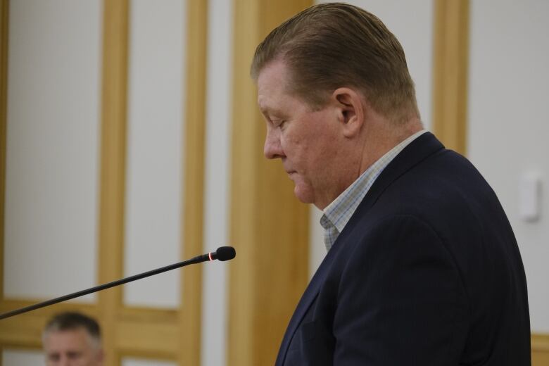 Keith Moen stands a microphone in the saskatoon city hall chambers.