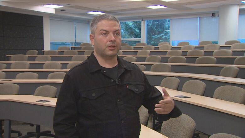 Raymond Sewell is standing in a classroom 