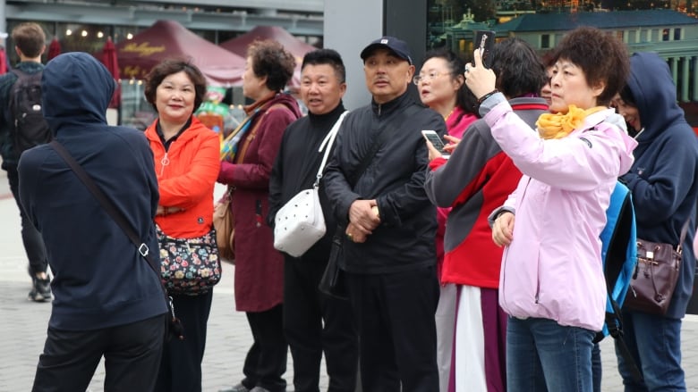 A number of East Asian tourists take pictures and mill around.