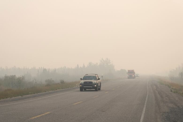 Vehicles on a highway as they leave Yellowknife with smoke from wildfire permeating the air.