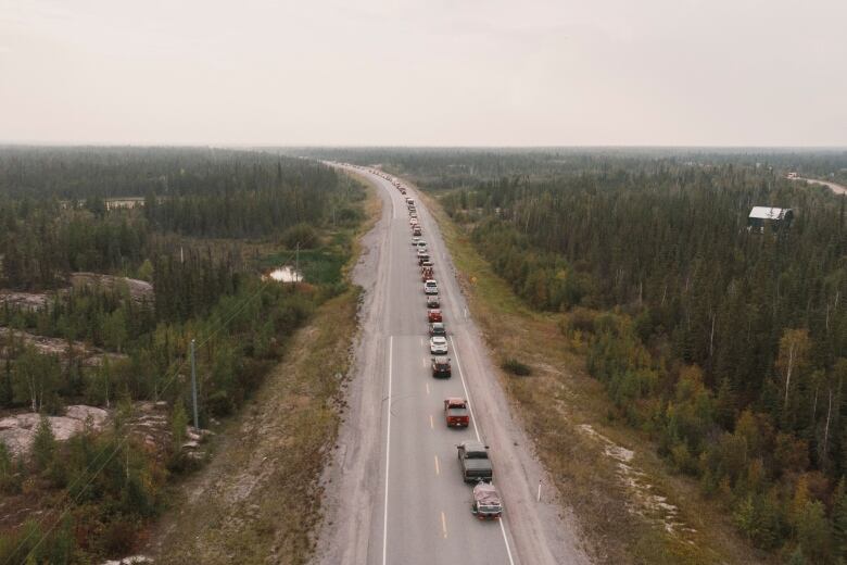 Vehicles form a single line stretching as far as the eye can see on a highway out of Yellowknife.