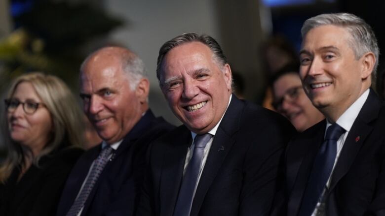 Three men smiling in an audience.