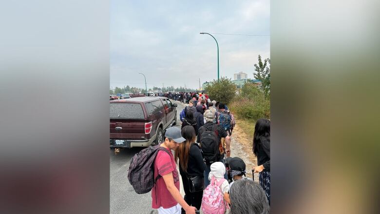 Line of people outside a high school. 