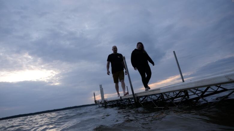 Alanna McIntyre and Tim May walk together on a pier on a Saskatchewan lake on a scuba diving outing.