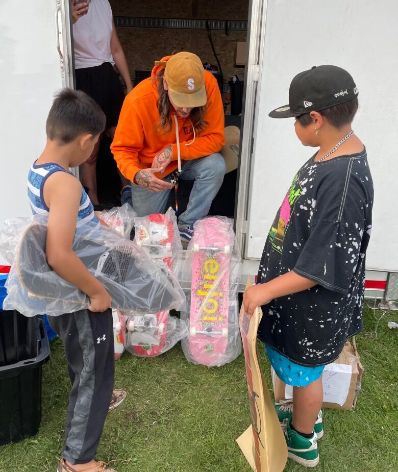 An AIG volunteer hands CJ and Ethan new skateboards.