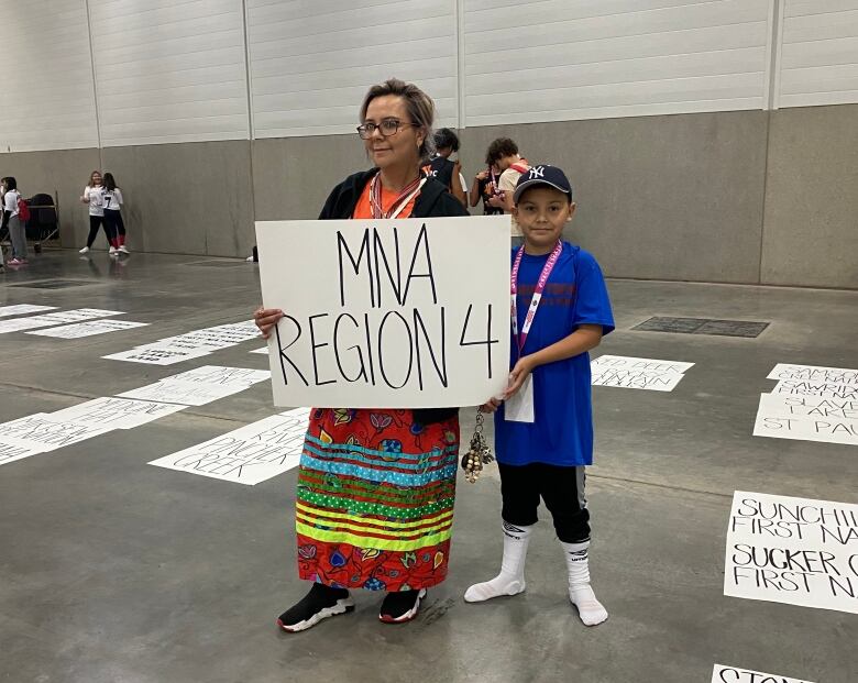 Lacey and Ethan stand holding a sign that represents the Mtis Nation of Alberta Region 4. 