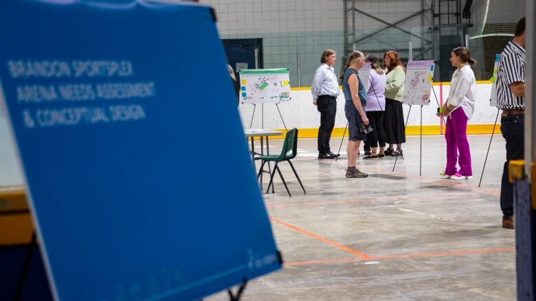 A group of people stand in an arena looking at building concept boards. 