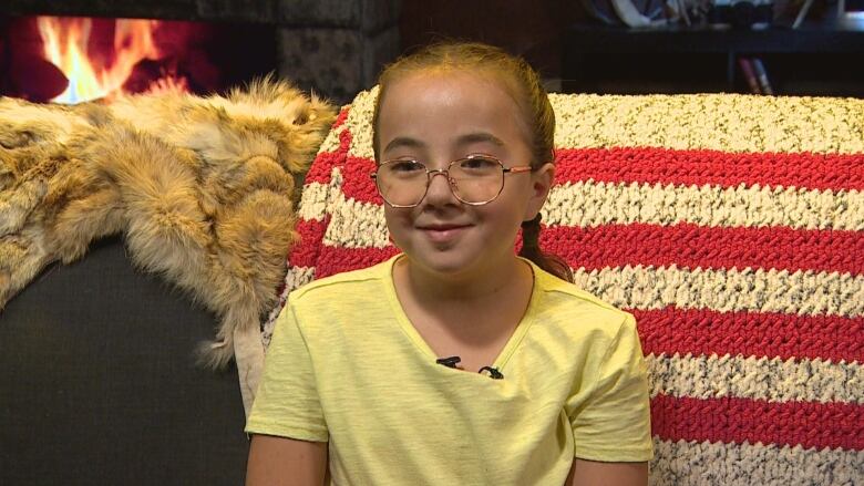 A girl wearing a yellow shirt can be seen smiling at the camera. 