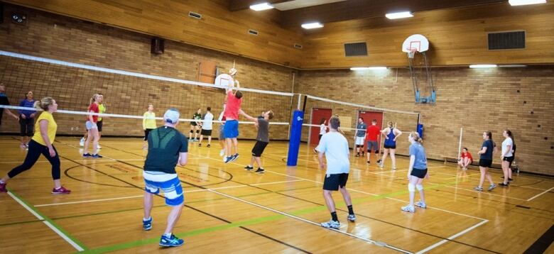 People play volleyball in an indoor court.