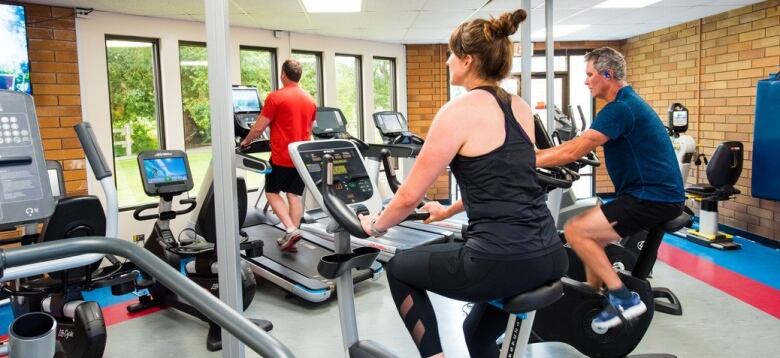 People use bicycle and treadmills inside a gym.