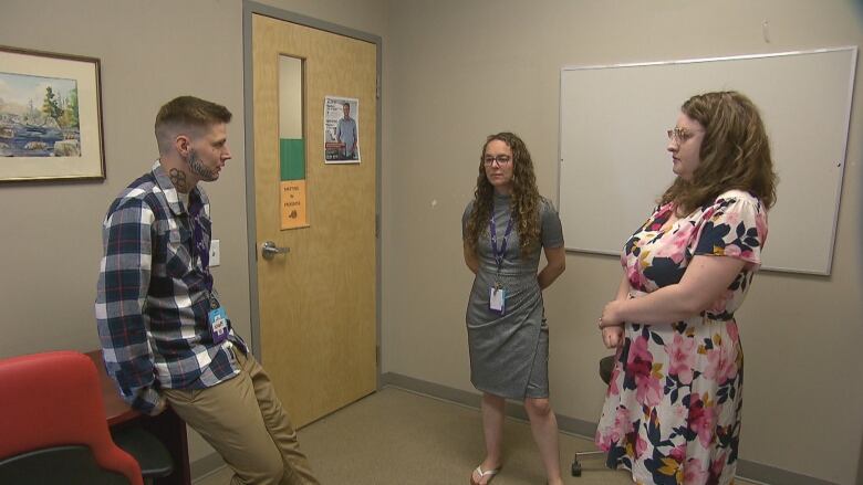 Three people stand in a room and hold a meeting before meeting clients at a clinic in Moncton.