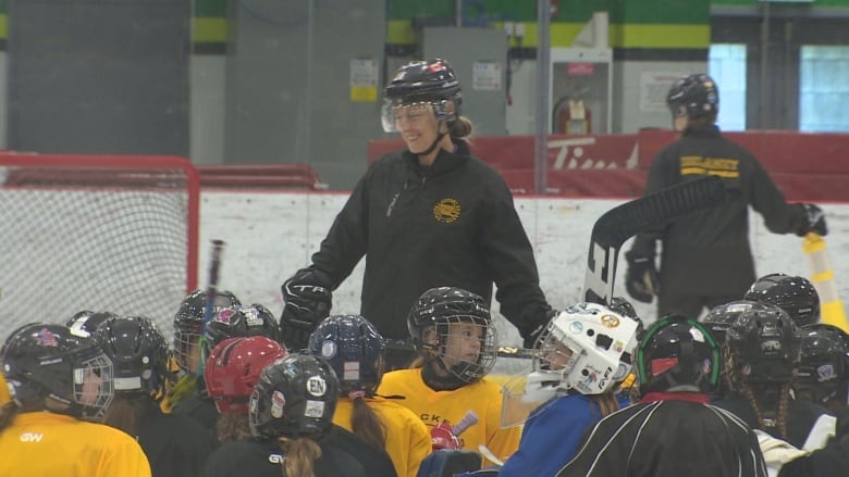 Woman on ice surrounded by young hockey players