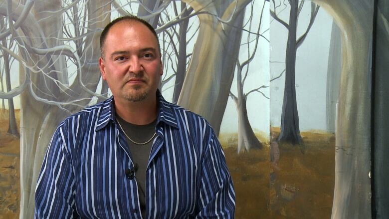 A man wearing a blue striped shirt over a dark grey shirt