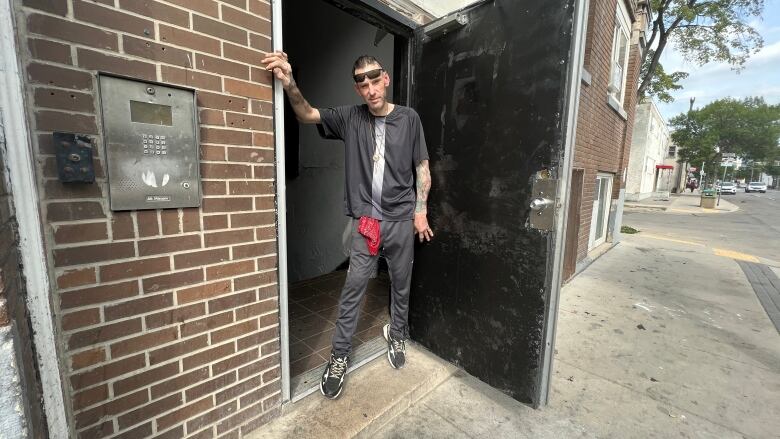 A man stands in the doorways of an apartment building.