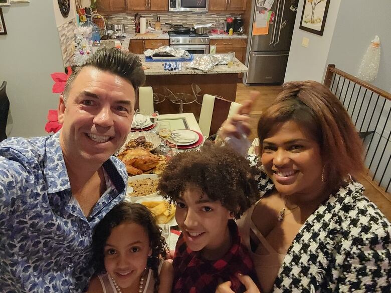 A white man, two children and a Black woman pose for a picture in a dining room.