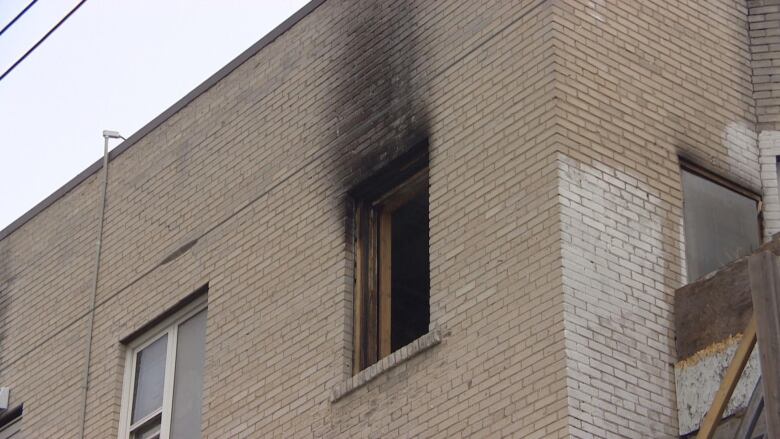 A gaping hole where a window used to be is shown on an apartment, with the remnants of black smoke at the top of it.