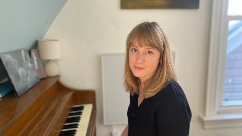 A woman sits at a piano.