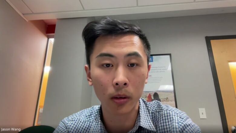 A man speaking via Google Meet videoconferencing from an office building.