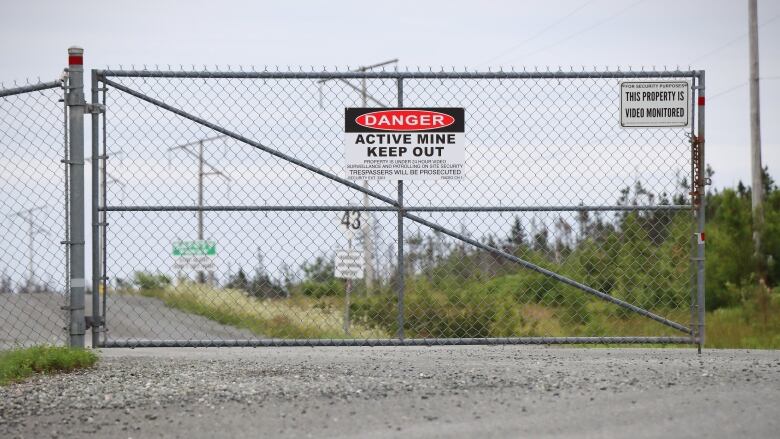 A chain link gate is shown with a sign saying 'Danger Active Mine Keep Out.'