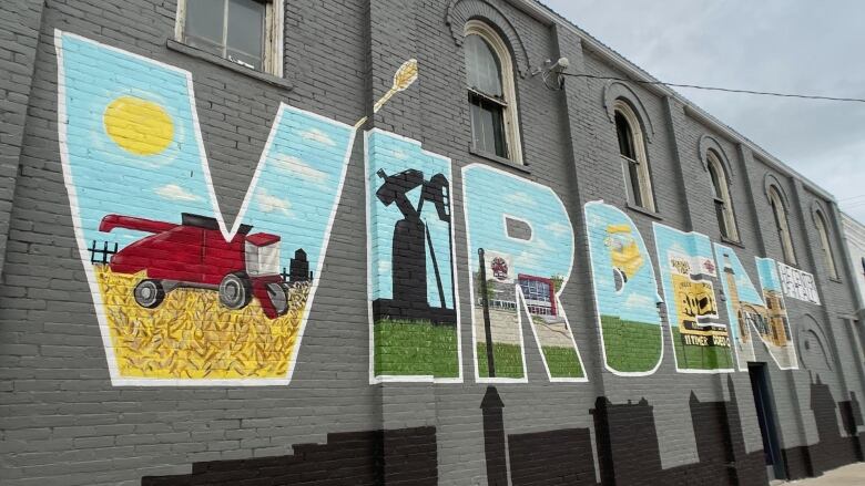 In Virden, a painted mural decorates a brick wall. The town name, Virden, is illustrated with symbols from the agricultural and oil industries.