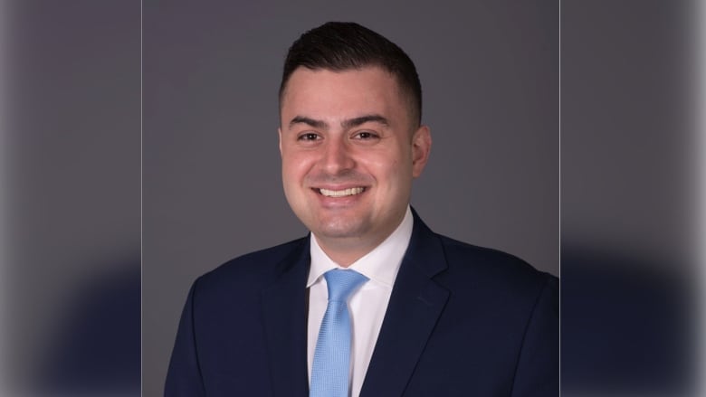 A man in a suit smiles for the camera.