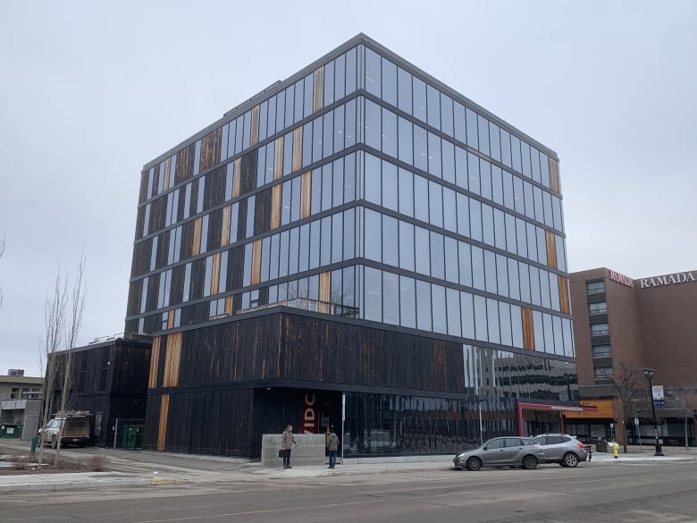 A multi-storey building with tall glass windows and wooden exterior.