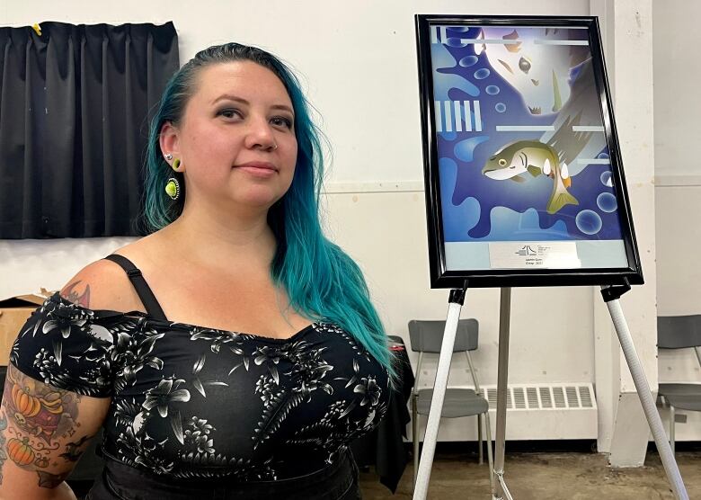 Jasmin Gunn standing next to her digital artwork of a bear ready to eat a salmon.  