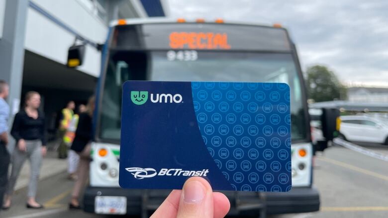 A blue Umo card is held up in front of a B.C. Transit bus.