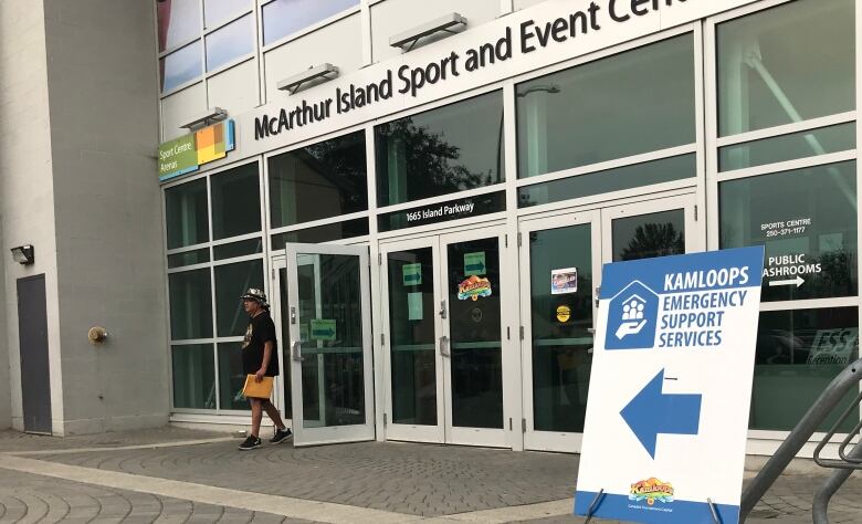 A man walks out of a building with a sign reading McArthur Island Sport and Event Centre.