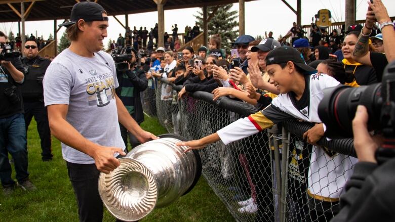 A young man carries the Stanley Cup for people to touch.