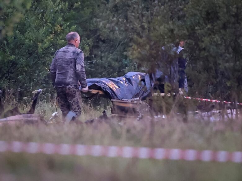 Emergency specialists carry a body bag near wreckages of the private jet linked to Wagner mercenary chief Yevgeny Prigozhin at the crash site in the Tver region, Russia, August 24, 2023. 