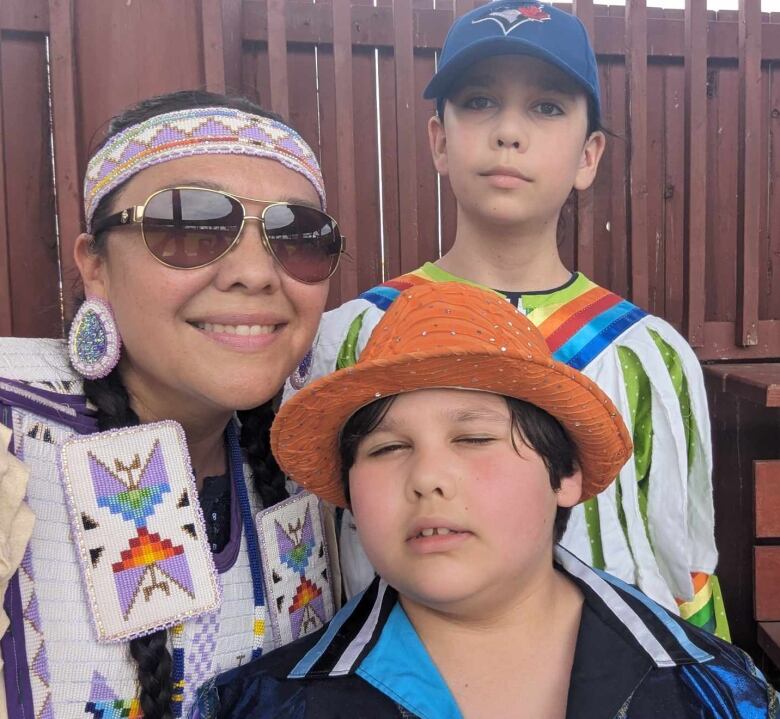 A photo of a mother with her two children in their regalia. 