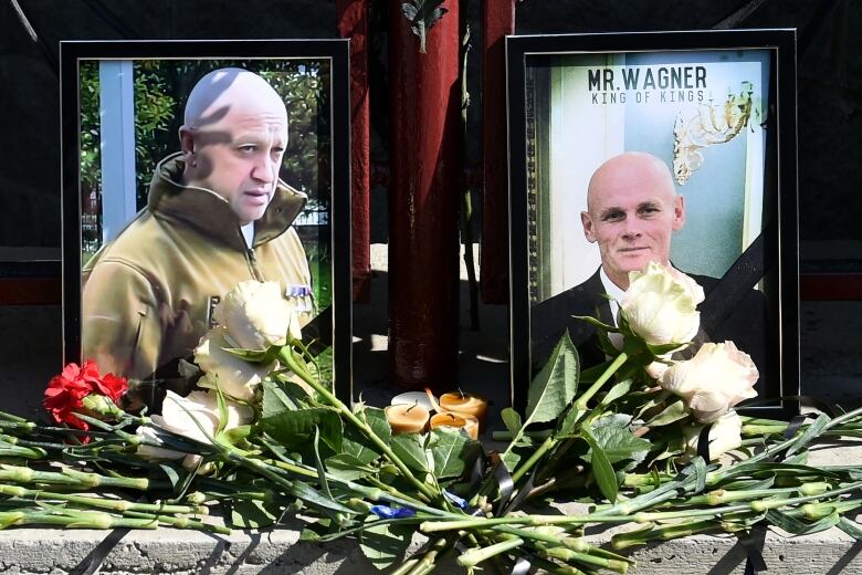 Two men are shown in framed photographs, with flowers laying before the photos.