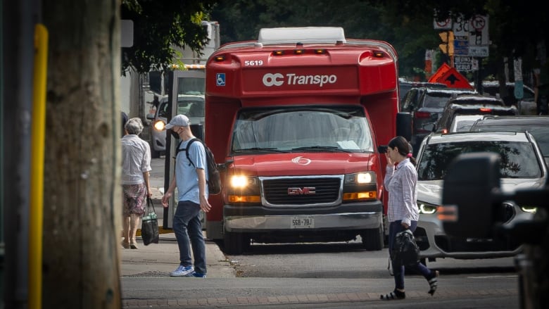 A red and white accessible transit minibus stopped on a city street in summer.