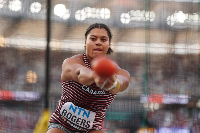 A Black woman concentrating on her turn during the hammer throw qualification round at the World Athletics Championships, shot with a slower shutter speed to blur the background.