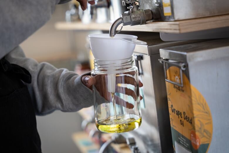 Staff at NU Grocery Store in Ottawa fill a jar with cooking oil.