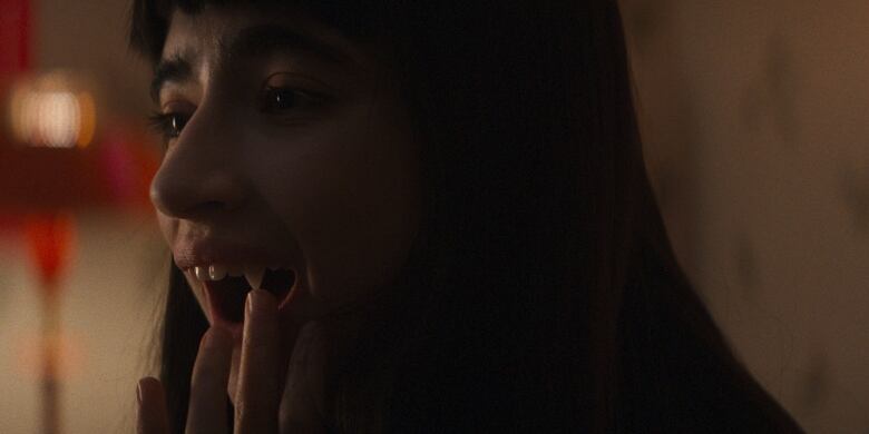 Still frame from the film Humanist Seeking Consenting Suicidal Person. Closeup of Sara Montpetit touching her fangs.