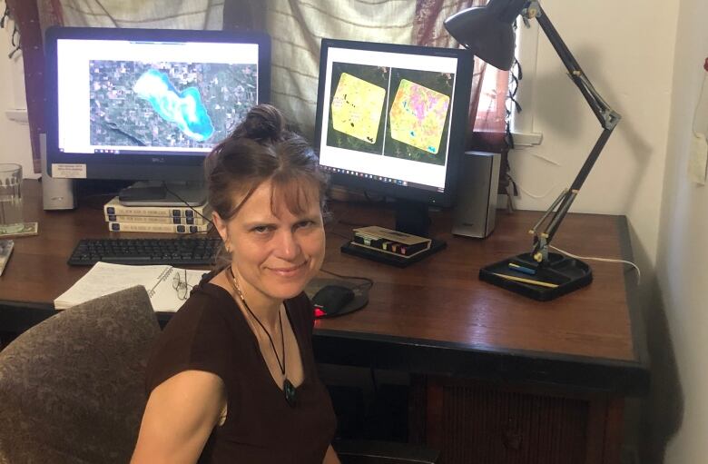 A woman sitting in front of computer screens. 