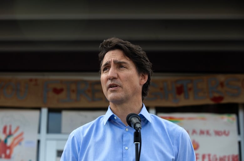 Prime Minister Justin Trudeau, wearing a blue collared shirt, speaks at a microhpone.