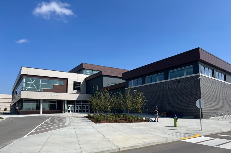 A large new looking building. It is white, brown and black and 'L' shaped. 