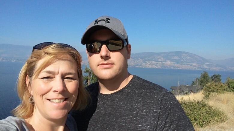 A woman stands with a man with a ball cap.