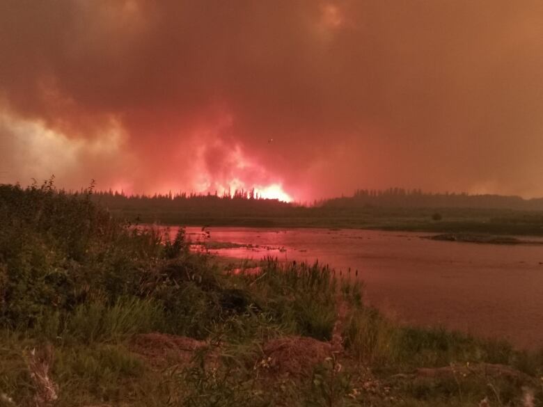 Fire billows into the air above water.