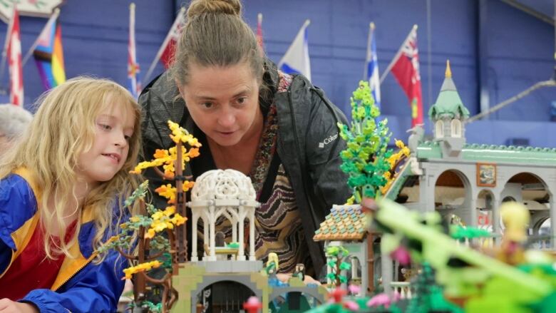 A woman and her child look closely at some fo the Lego work. 