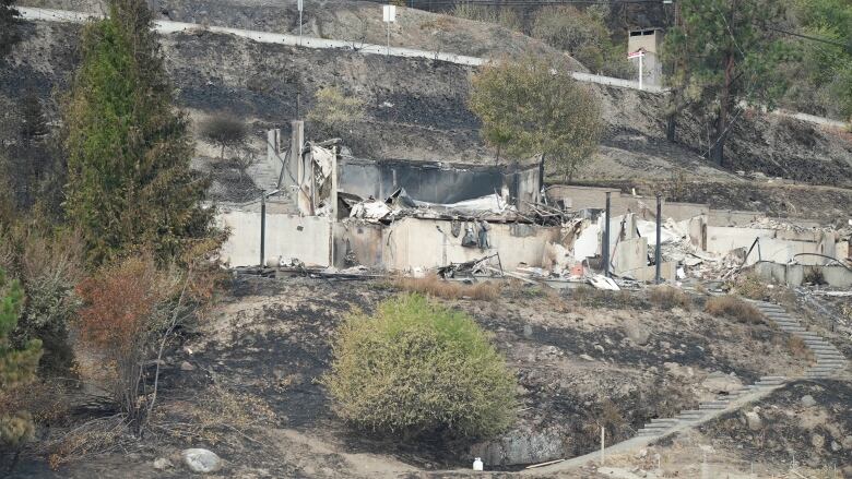 Charred remains of a home on a hillside.