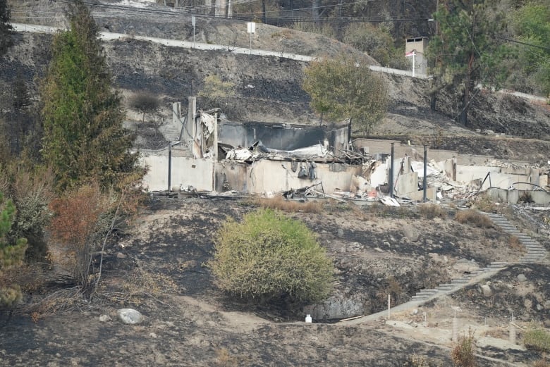 Charred remains of a home on a hillside.