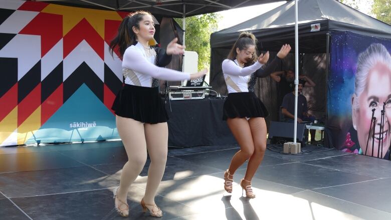 Two salsa dancers are seen performing on a stage.